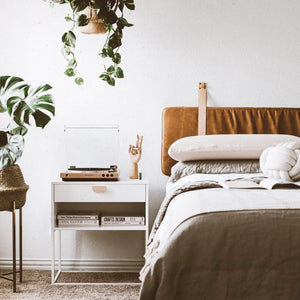 Bedroom with plants, side table with books, record player placed next to the bed with a Honey Leather Wall Mounted Headboard Cushion with Natural Straps.
