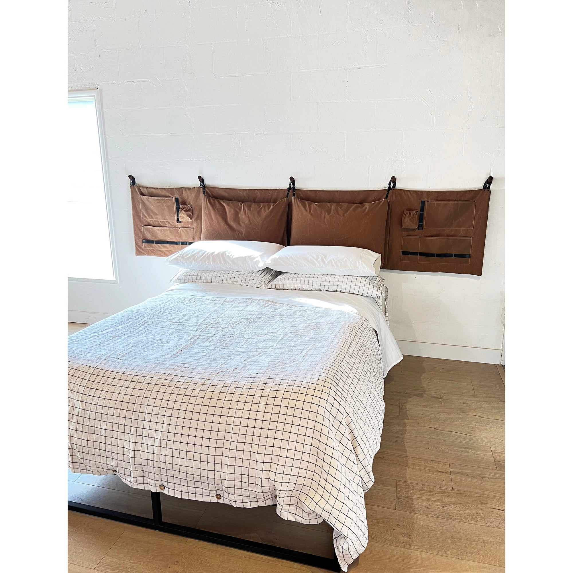 Platform queen sized bed with magic linen bedding makes up a modern bed when matched with the wall-hung brown waxed canvas headboard. 