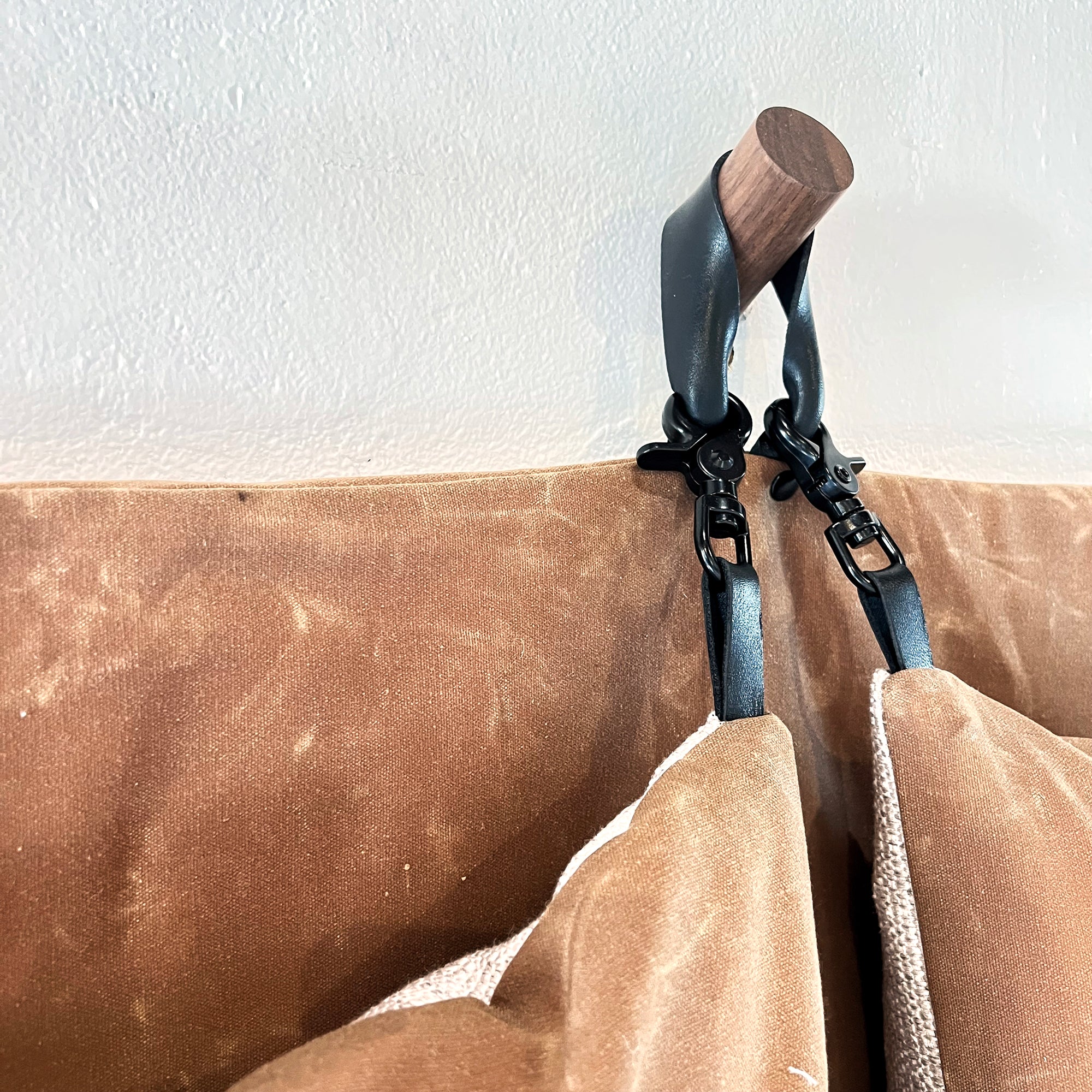Black clasps attached to leather loops on the pillow corners show the rugged versatility of being able to change out the pillows with ease.
