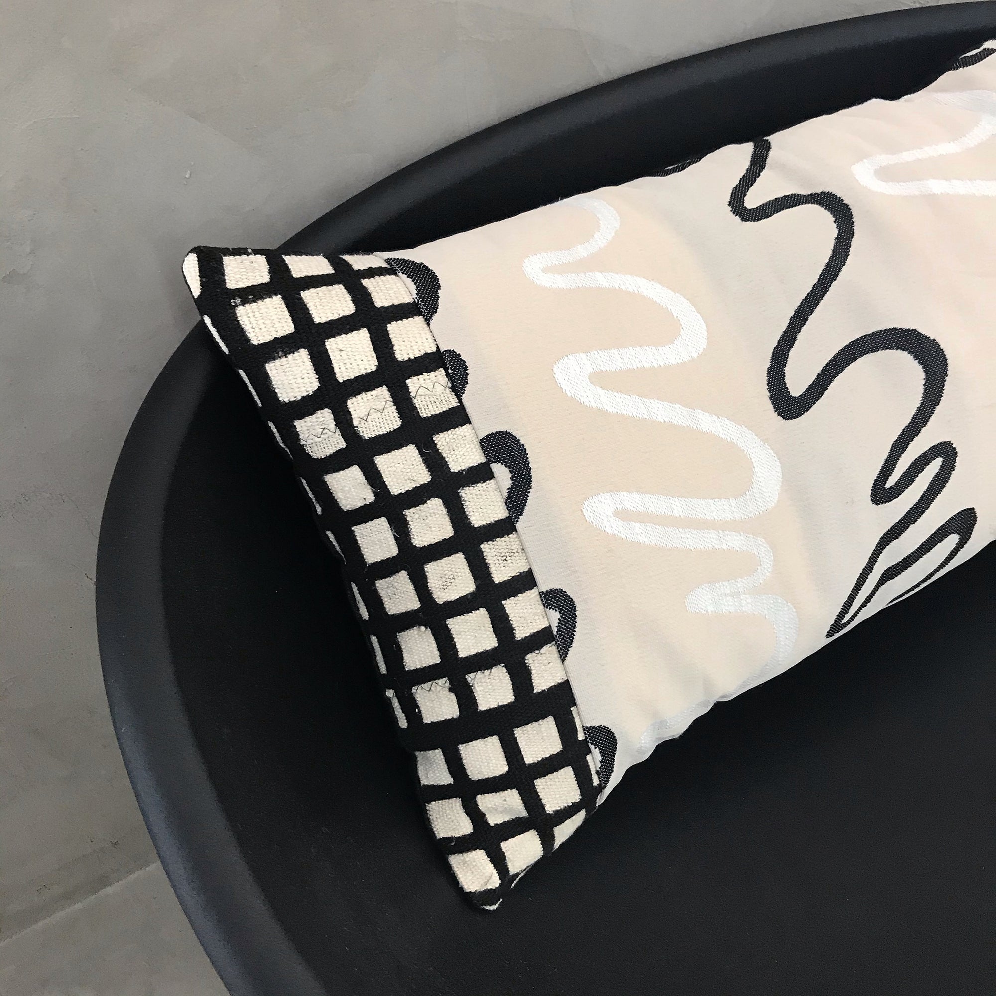 Detail pattern shot of the black grid, white and black squiggles against the beige mudcloth fabric. Lumbar pillow.