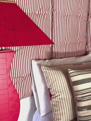 Video with music showcasing the details of the tuft wall cushion system - tomato red and off-white stripe linen hanging on the wall above a bed. 